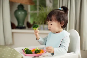 Ilustrasi anak balita makan sayuran.