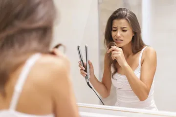 Ilustrasi perempuan mengalami kerusakan rambut akibat penggunaan alat pelurus rambut.