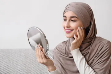 Ilustrasi perempuan berhijab sedang bercermin.