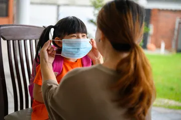 Ibu memakaikan masker pada anaknya
