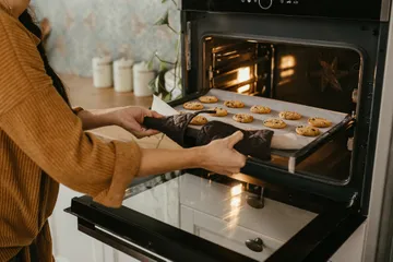 Membersihkan oven setelah digunakan memasak kue Natal.