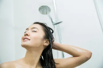 Perempuan sedang keramas dengan sampo sulfate free