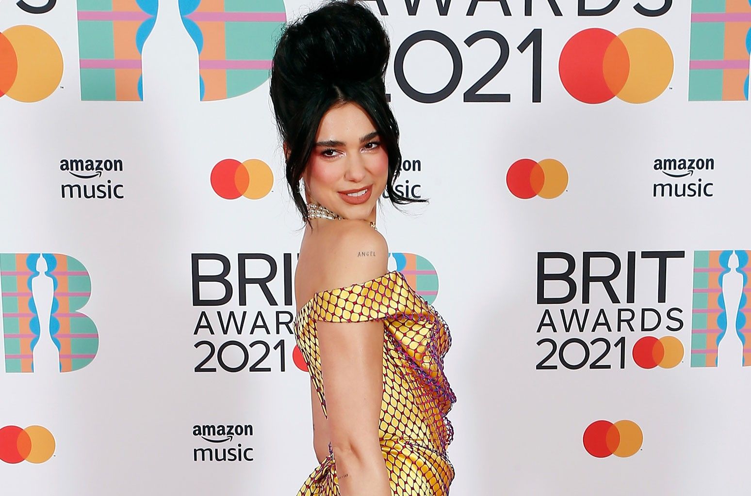 Dua Lipa hadir di Brit Awards 2021 dengan mengenakan gaun kuning pendek dan rambut yang disasak sebagai penghormatan pada Amy Winehouse.