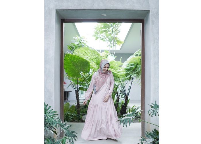Dewi Sandra dengan long dress Ria Miranda warna baby pink polos.