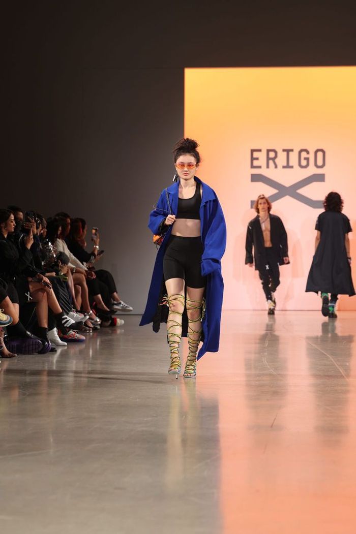 Model Erigo sedang berjalan di atas catwalk dengan long jacket biru