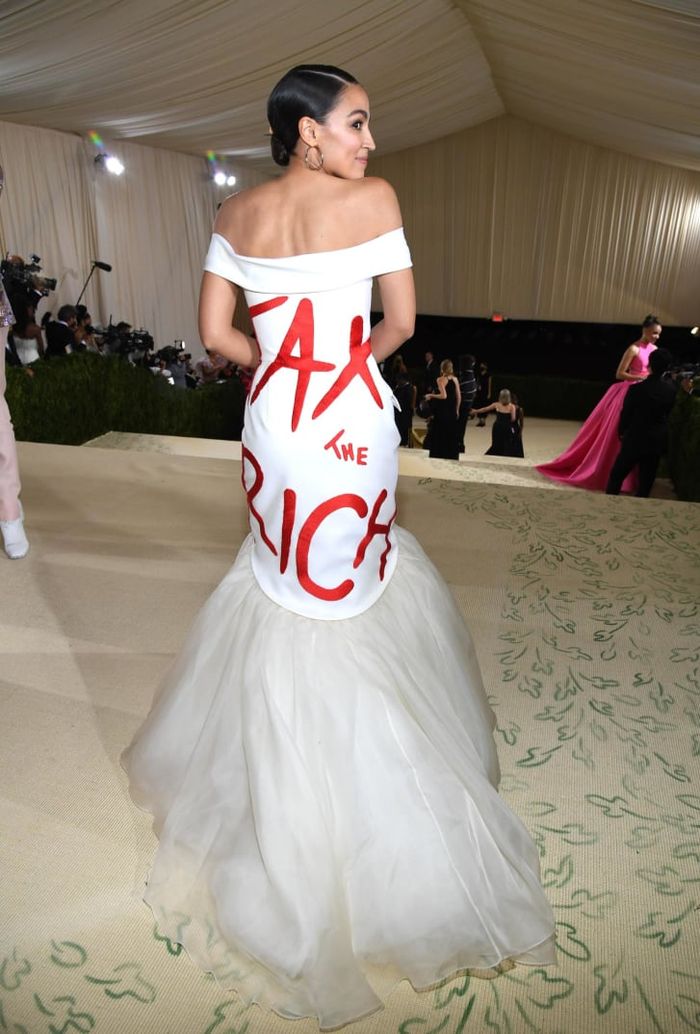 Alexandria Ocasio-Cortez mengenakan white off the shoulder dress dengan tulisan Tax the Rich.