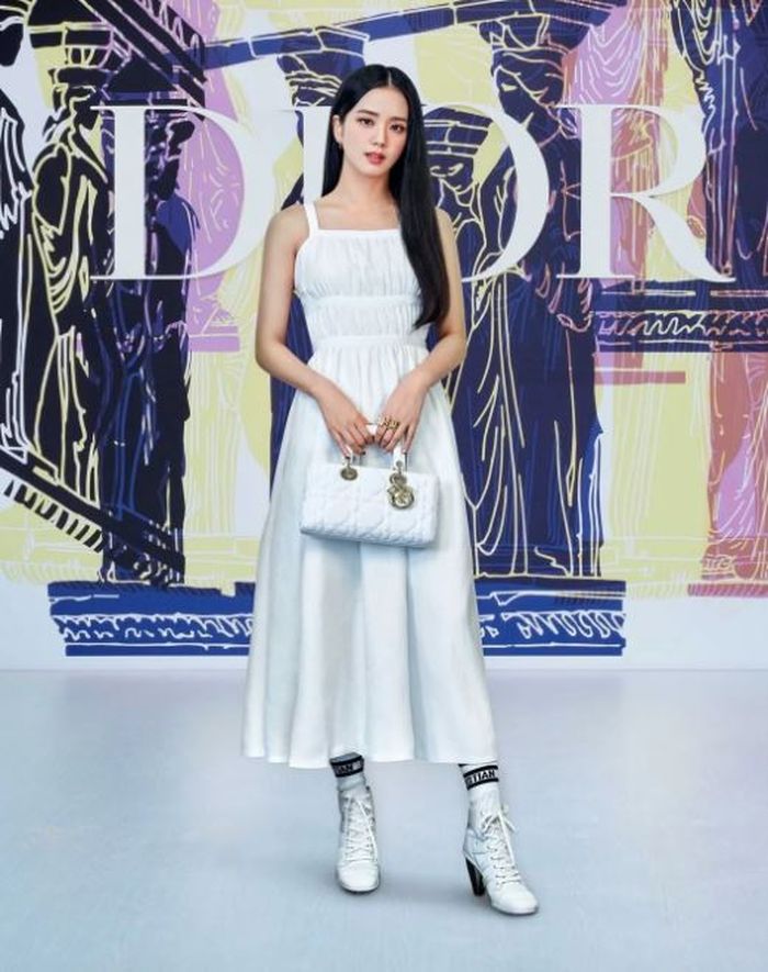 Jisoo Blackpink mengenakan dress putih dengan handbag Dior.